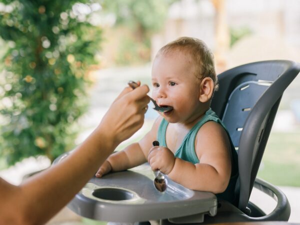 UN bébé mange sur sa chaise-haute