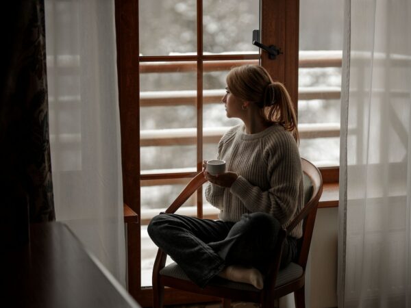 Femme regardant par la fenêtre en hiver ©Pexels