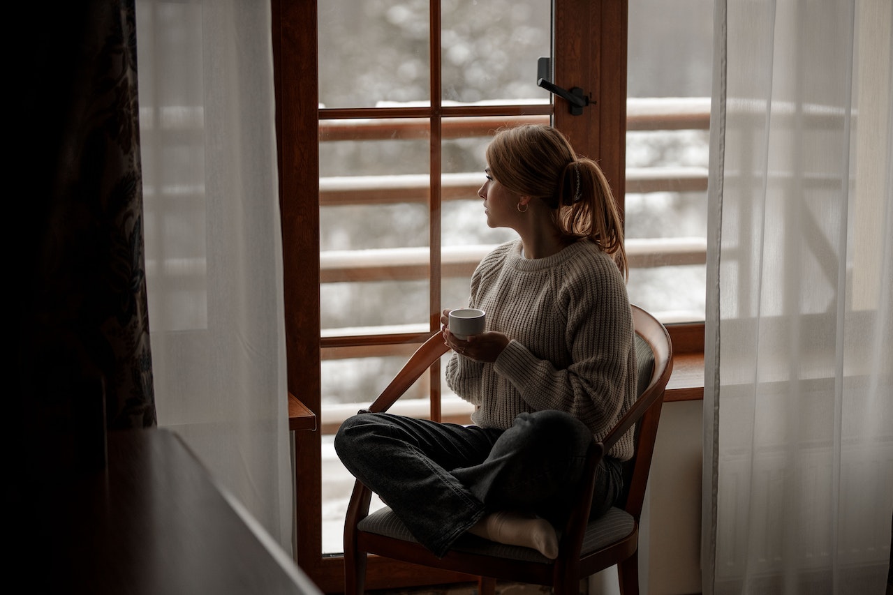Femme regardant par la fenêtre en hiver ©Pexels